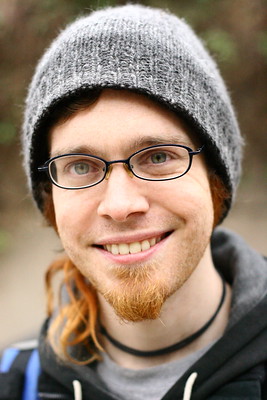 Portrait of Derek, white face with broad smile and glasses.